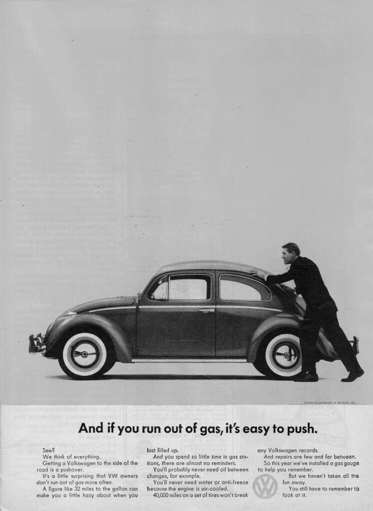 Black and white advertisement featuring a person pushing a Volkswagen Beetle. The text below reads, "And if you run out of gas, it's easy to push." The background is plain with the focus on the car and the person leaning against it.