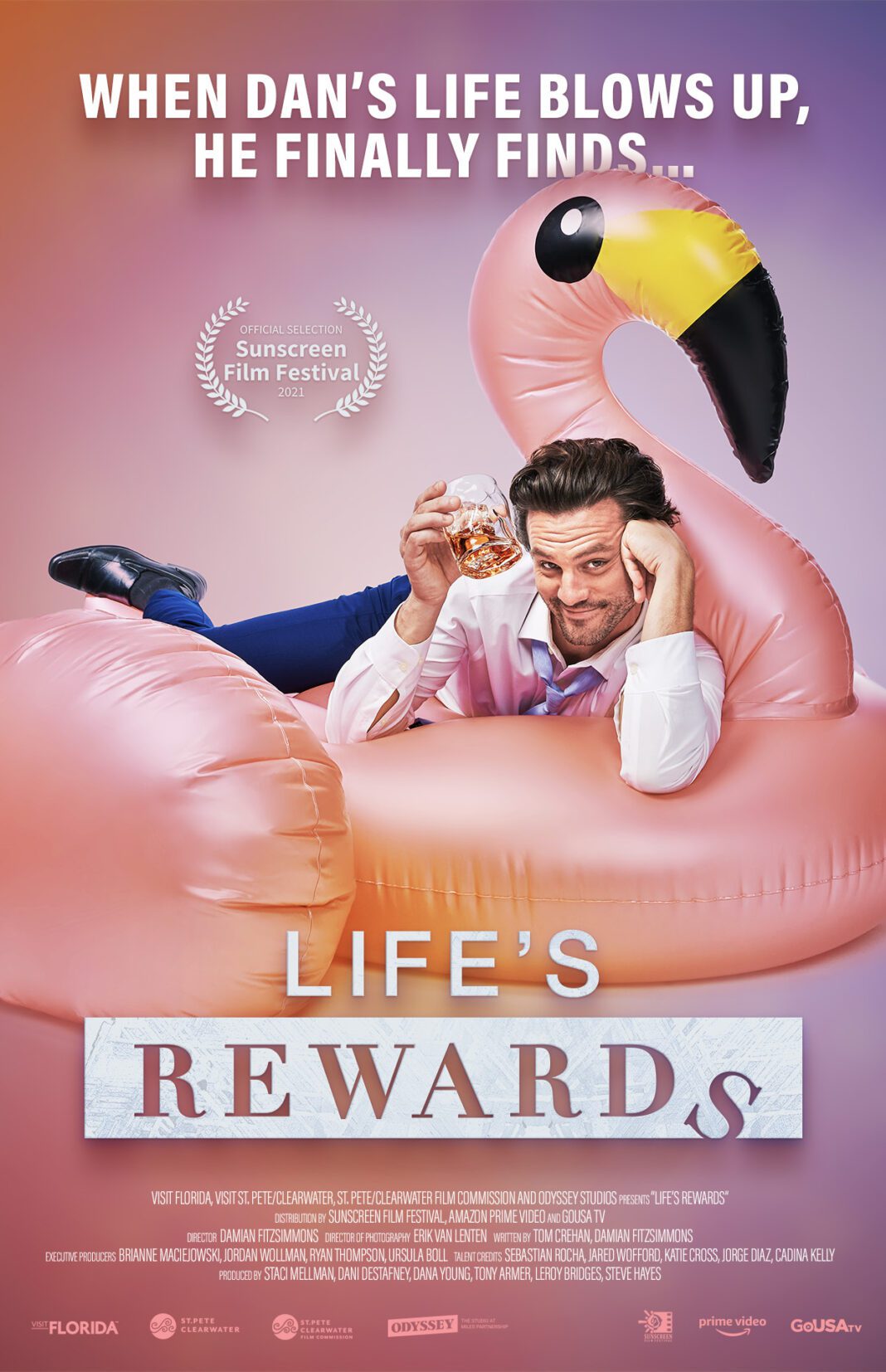 A man in a blue suit lounges on a large inflatable pink flamingo, holding a glass with a drink. The text above reads, "When Dan's life blows up, he finally finds..." and below, "Life's Rewards." Various film logos and credits are shown.